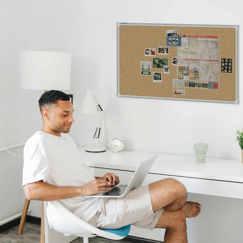 Cork pin board in stylish home office setting with photos and maps, ideal for organising notes and inspiration.