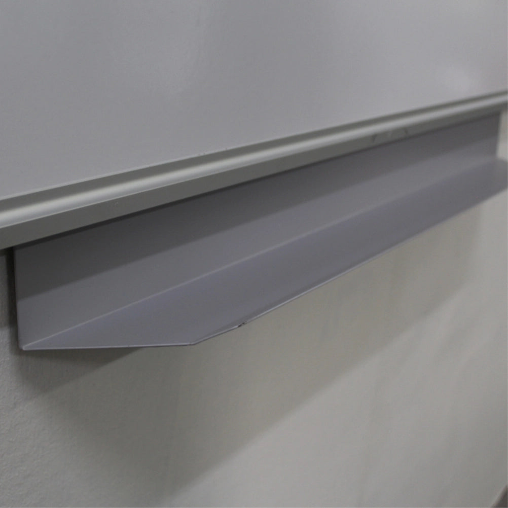 Close-up of a gray metal chalkboard lip or penrail mounted beneath a whiteboard on a white wall.