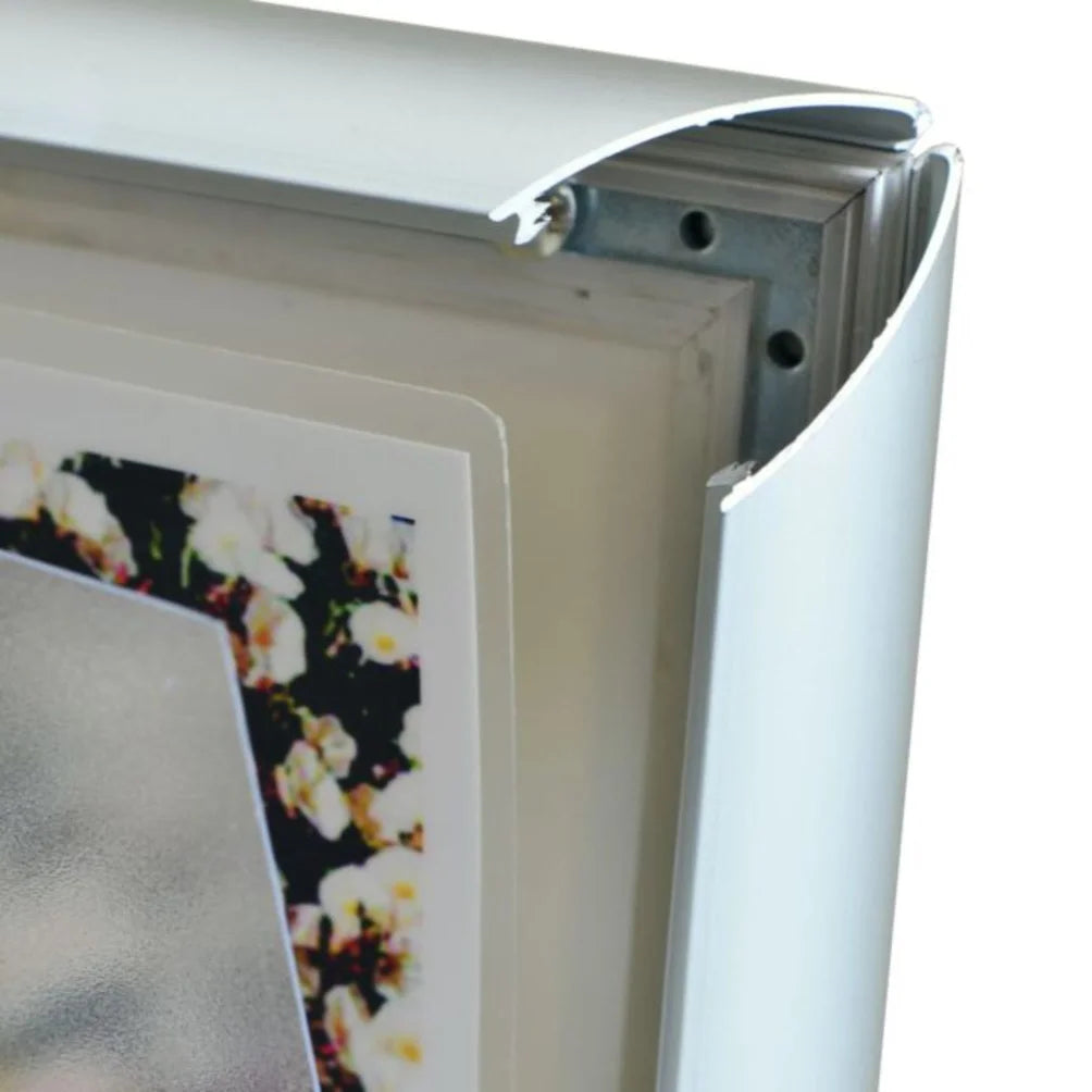 Close-up of a aluminium metal picture frame corner with a snap mounting bracket and a sample floral print partially visible inside.