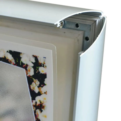 Close-up of a aluminium metal picture frame corner with a snap mounting bracket and a sample floral print partially visible inside.